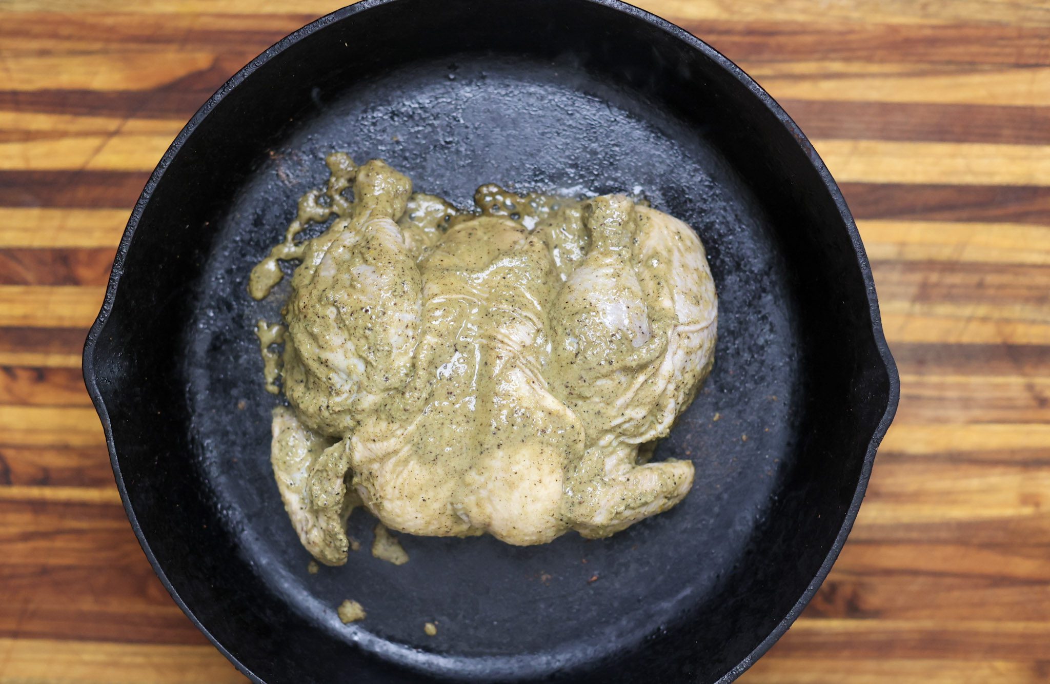 raw spatchcock chicken marinated in jerk marinade.