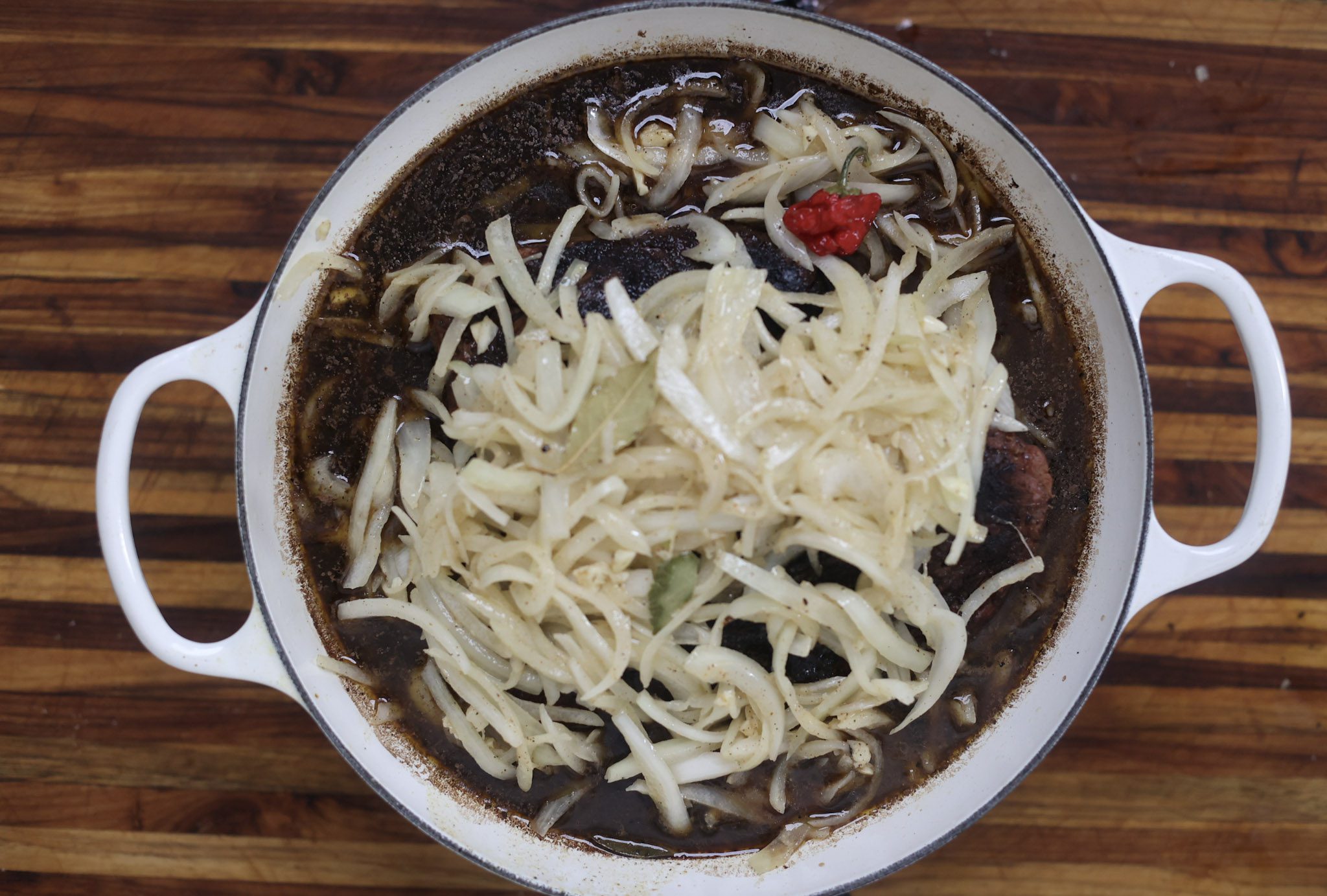 brisket braising in pot with onions on top