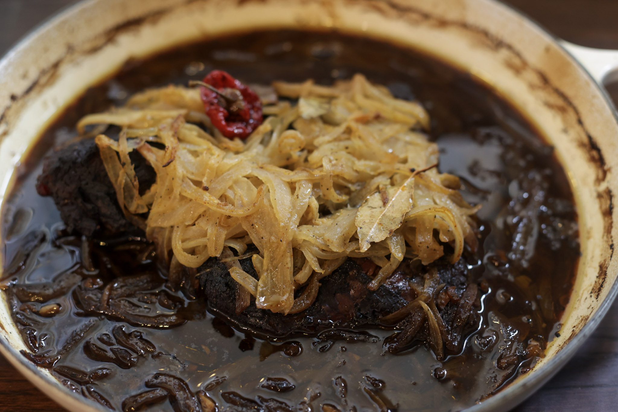 brisket braising in pot with onions on top