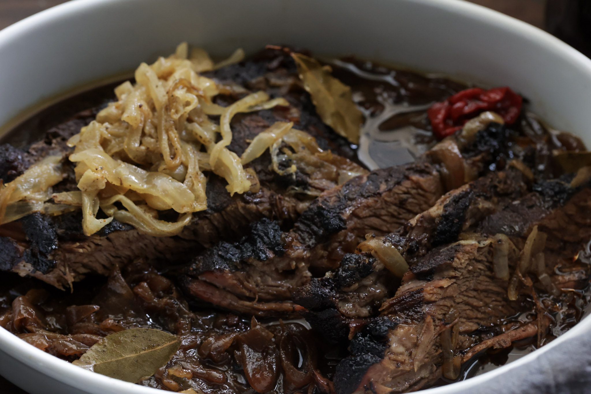 braised brisket and onions in a white bowl