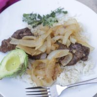 bistec encebollado with rice on plate