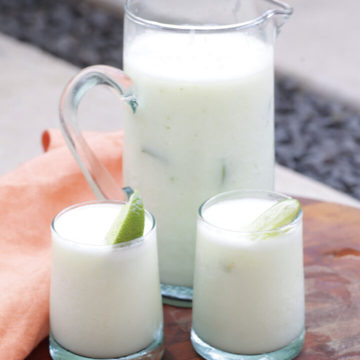 brazilian lemonade in a tall glass pitcher and two small glasses.