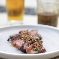 steak with chimichurri sauce on gray plate