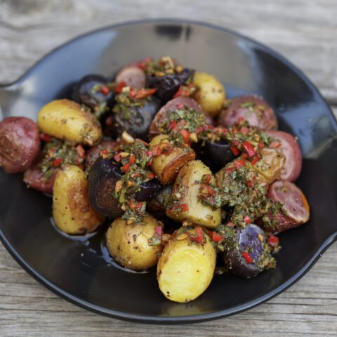 potato salad with chimichurri sauce on black plate