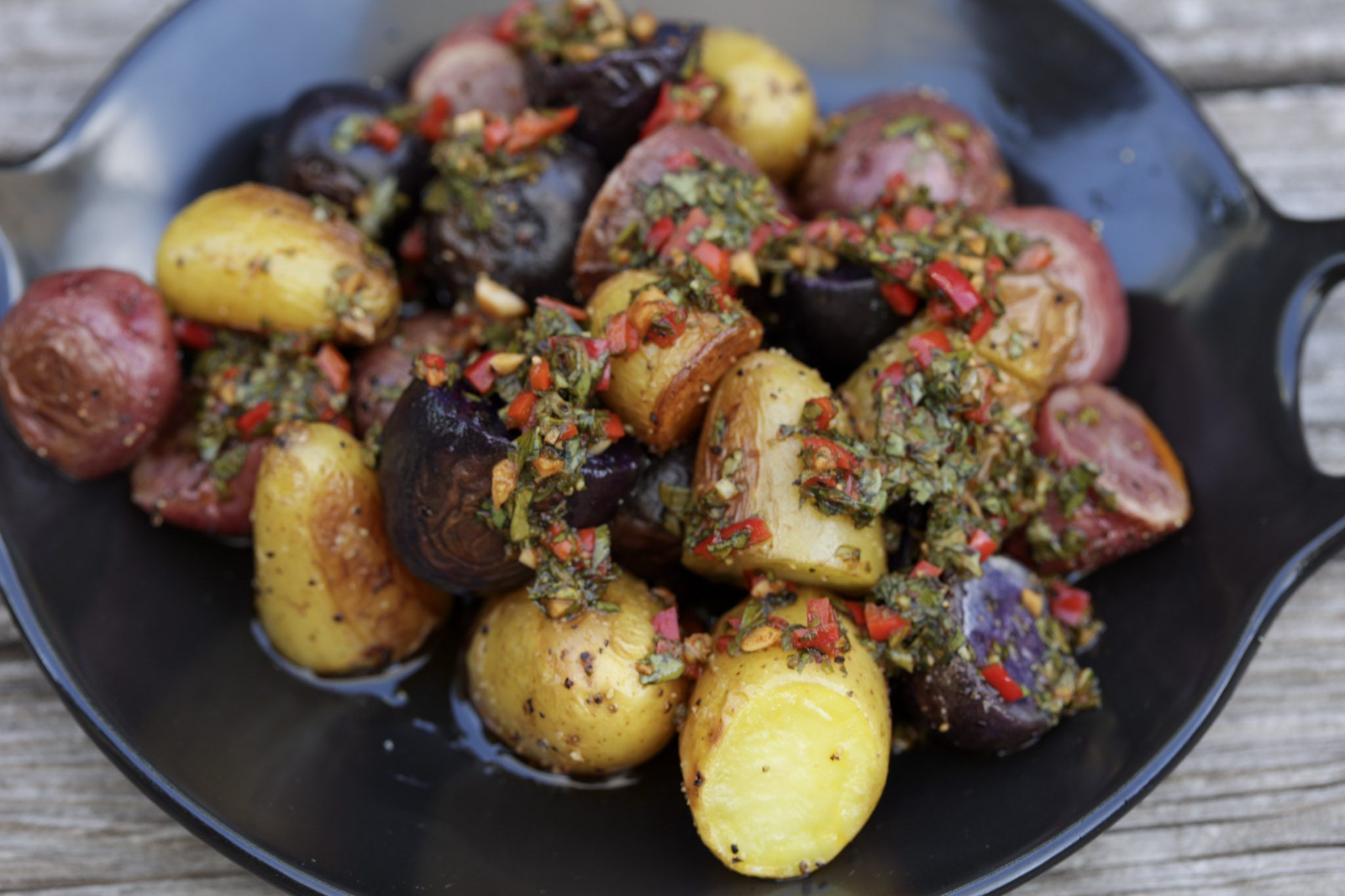 potato salad with chimichurri sauce on black plate