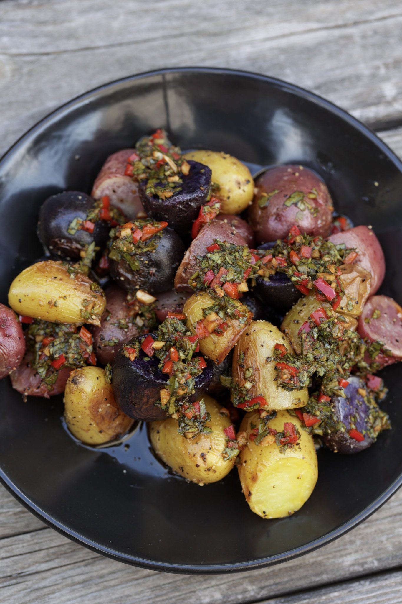 potato salad with chimichurri sauce on black plate