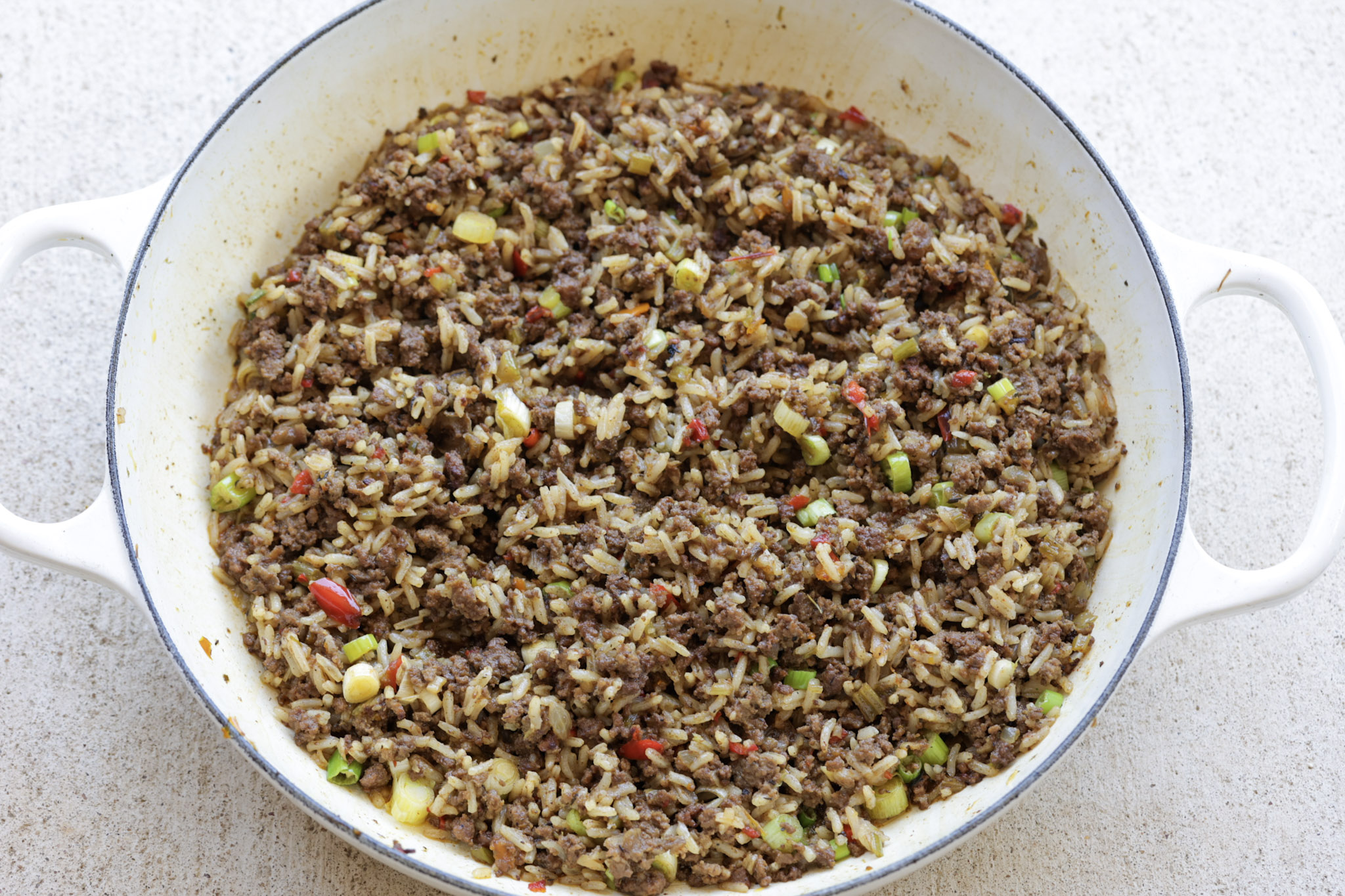 dirty rice in white cast iron pan