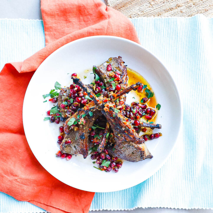 air fryer cooked lamb chops topped with pomegranate chimichurri on white plate