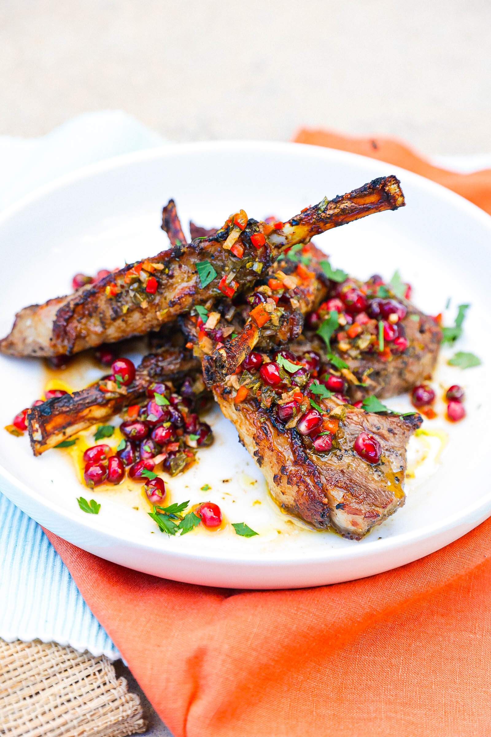 air fryer cooked lamb chops topped with pomegranate chimichurri on white plate