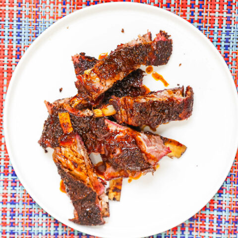 smoked lamb ribs topped with awaze sauce on white plate