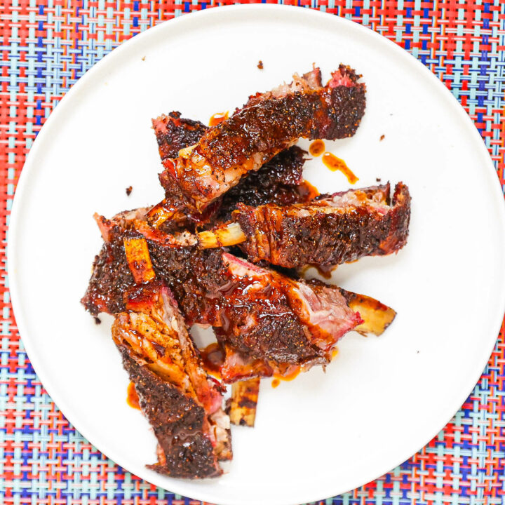 smoked lamb ribs topped with awaze sauce on white plate