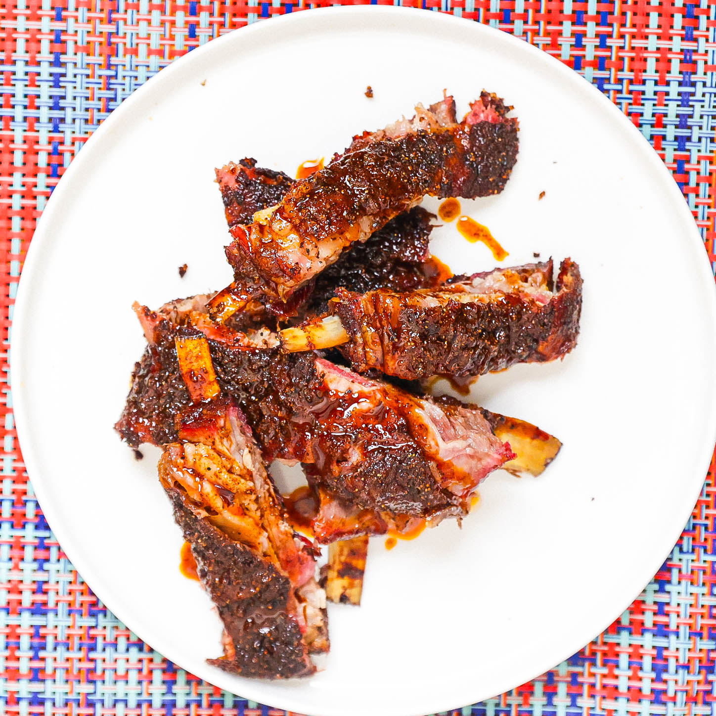 smoked lamb ribs topped with awaze sauce on white plate