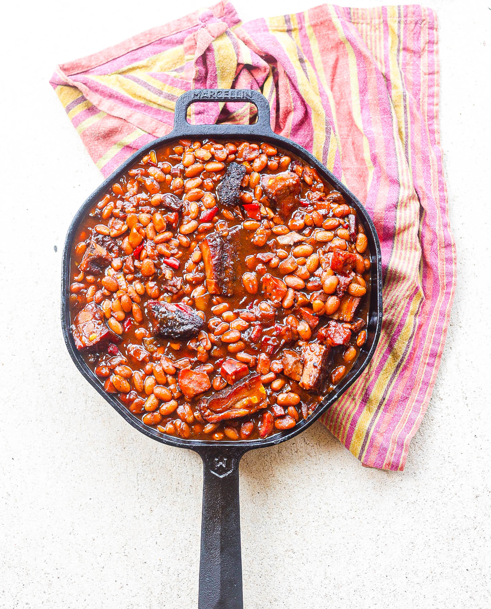 bbq beans with smoked meats in black cast iron skillet