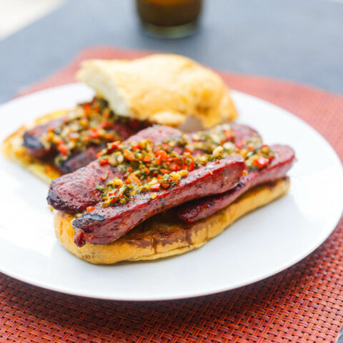 open face choripan sandwich on a white plate