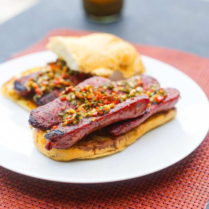 open face choripan sandwich on a white plate