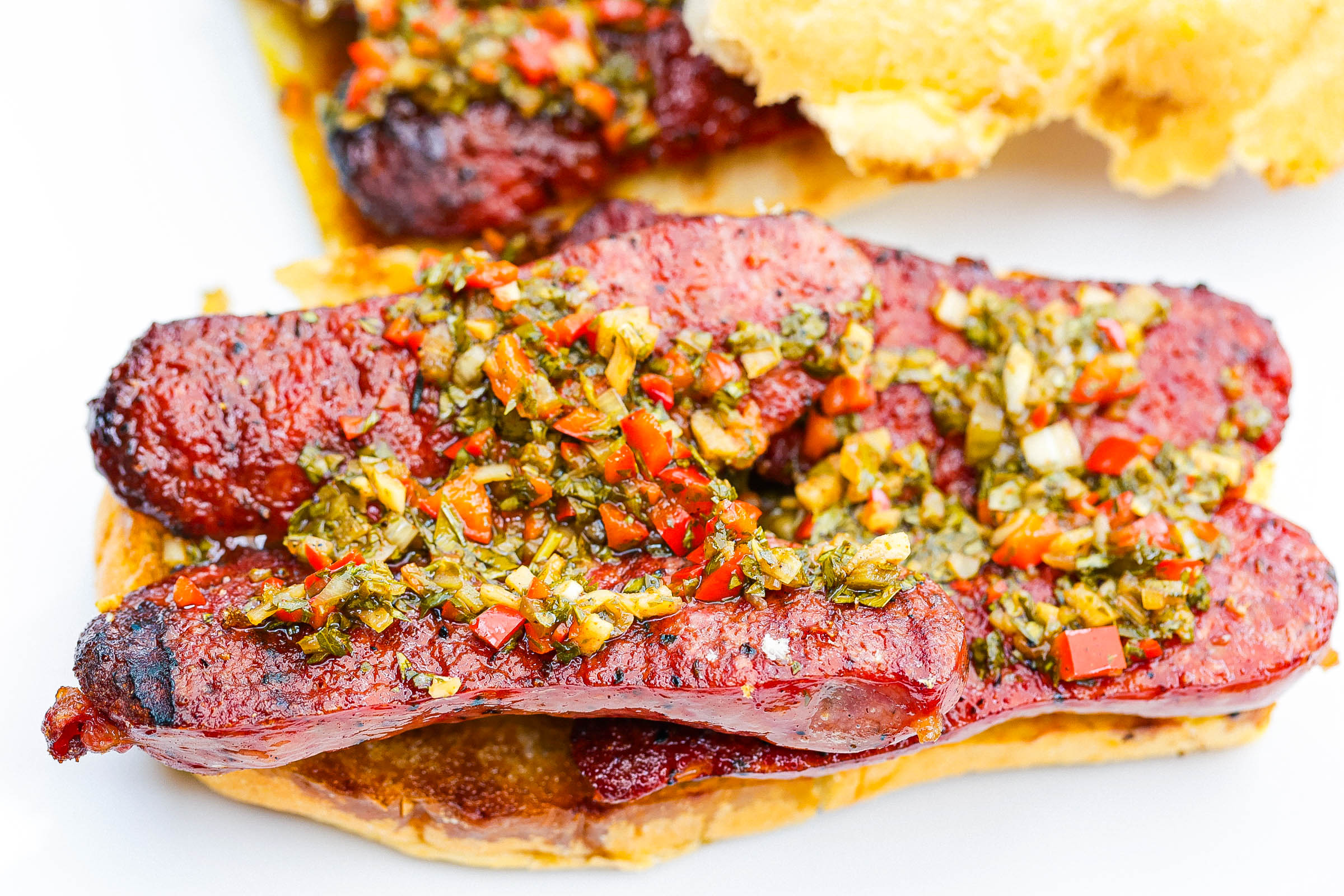 open face choripan sandwich on a white plate