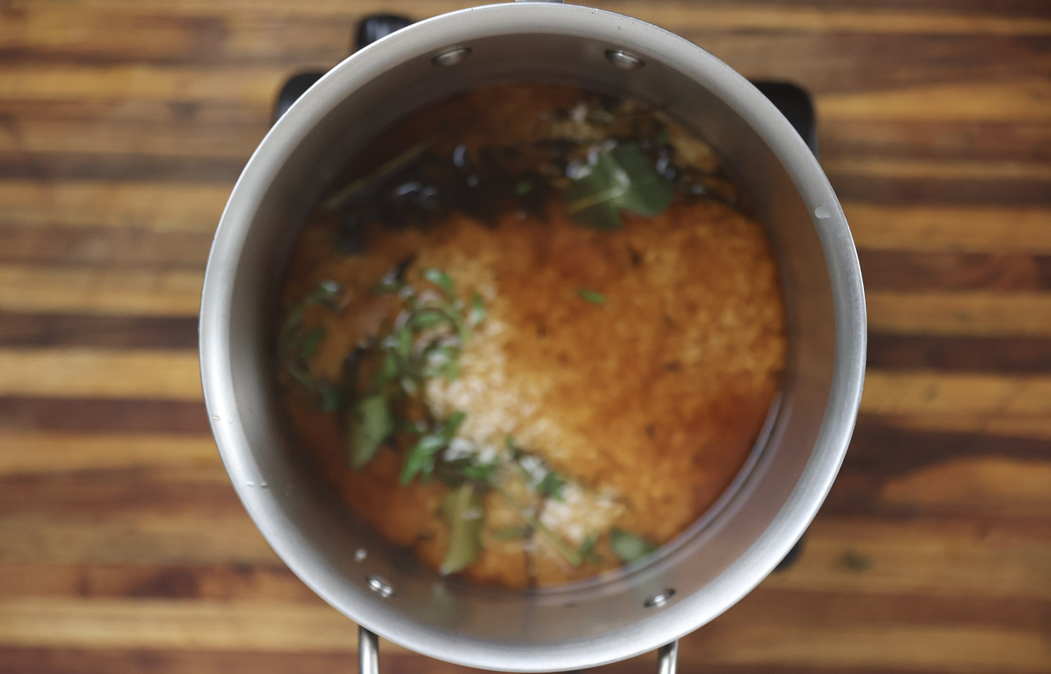 rice cooking in pot with beef broth and fresh herbs