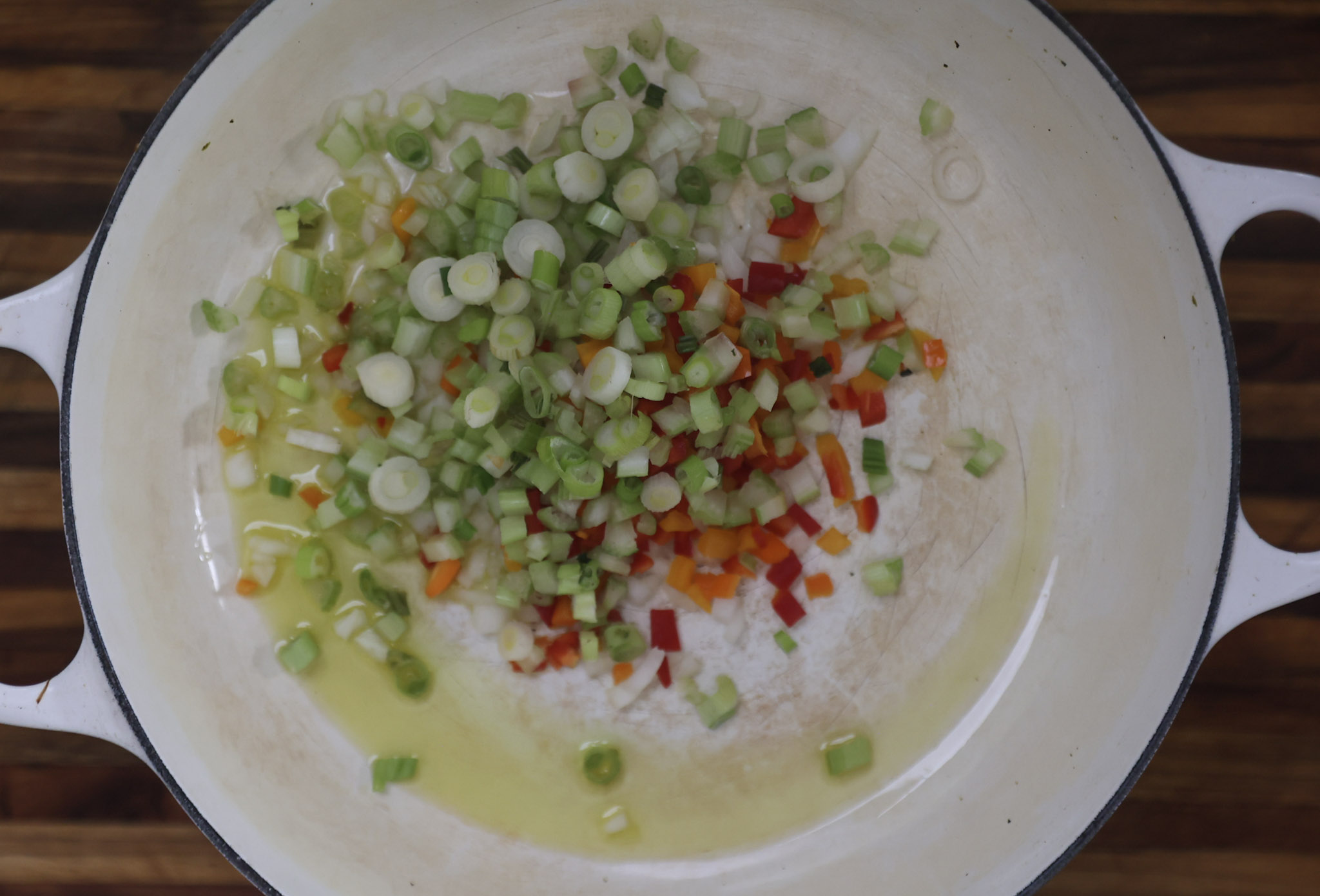 green onions, onions, bell peppers, and celery sauteing in pan