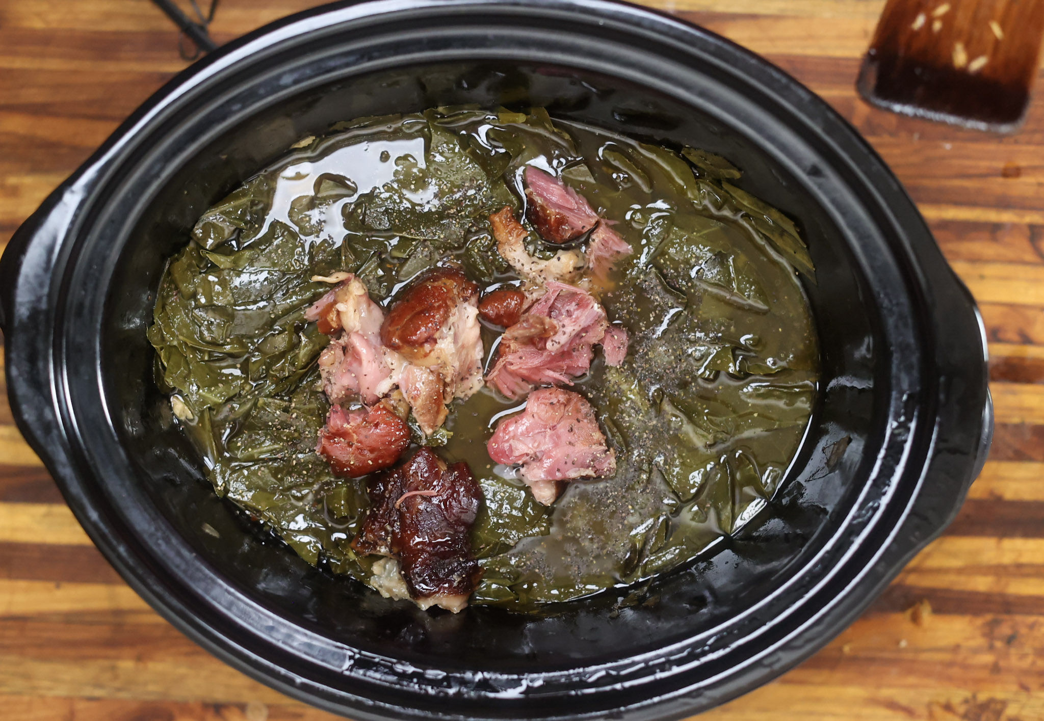 slow cooker collard greens with ham hocks in crockpot bowl