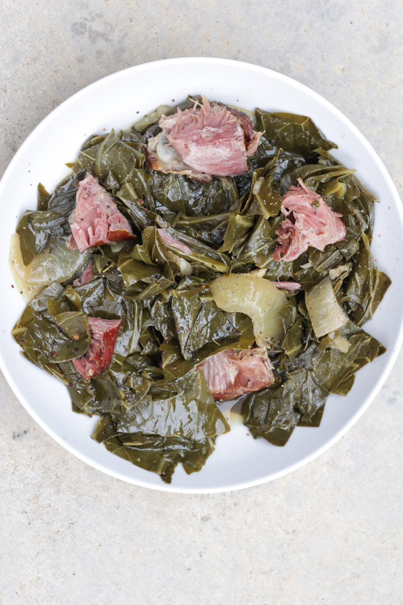 slow cooker collard greens with ham hocks in white bowl