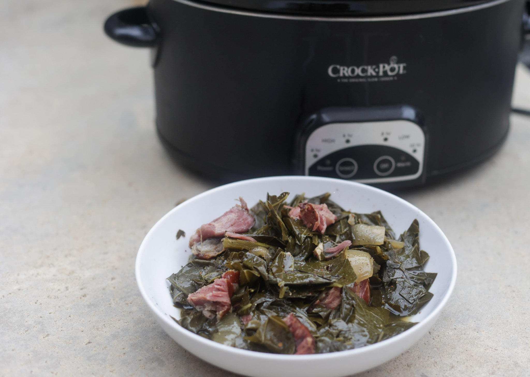 slow cooker collard greens with ham hocks in white bowl